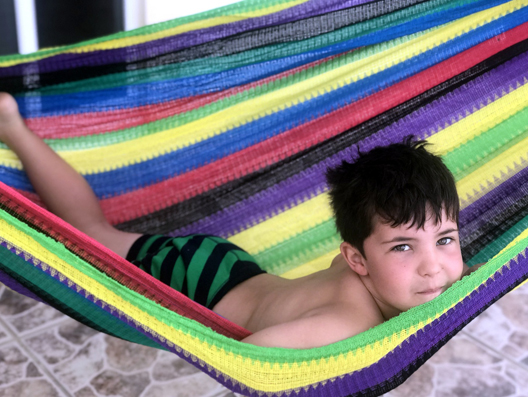 boy playing in a hammock on the beach